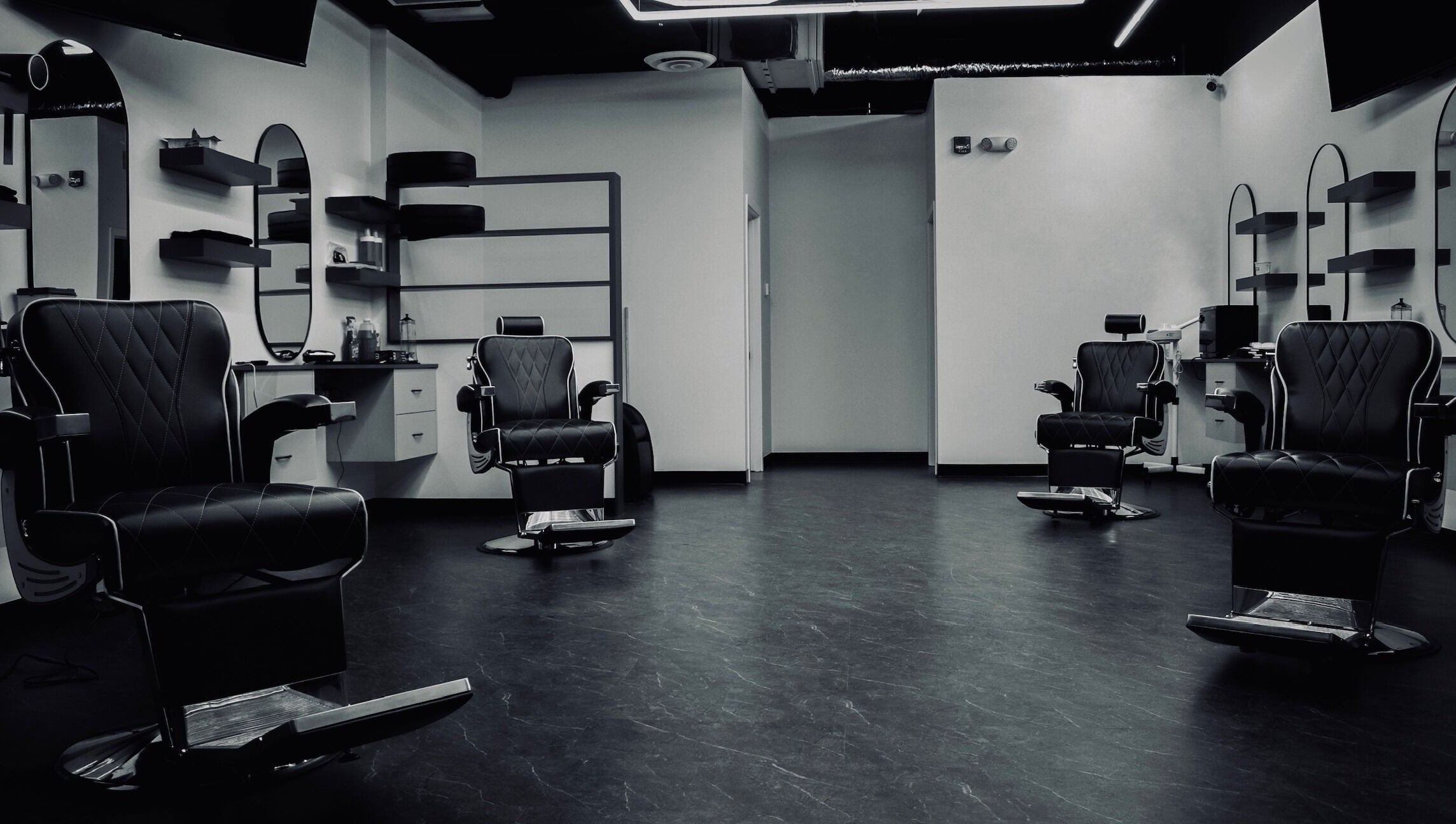 Modern interior of Platinum Barbershop in Edmonton, Alberta, CA, showcasing stylish black chairs and mirrors.
