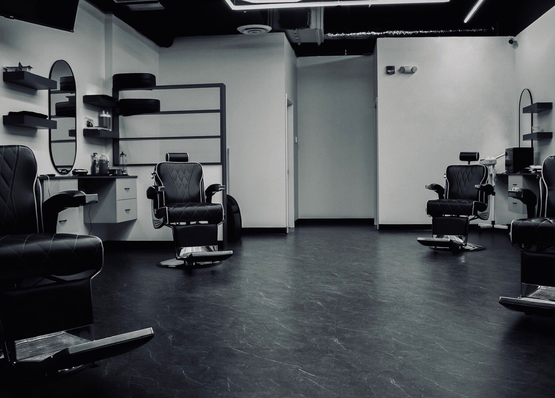 Modern interior of Platinum Barbershop in Edmonton, Alberta, CA, showcasing stylish black chairs and mirrors.