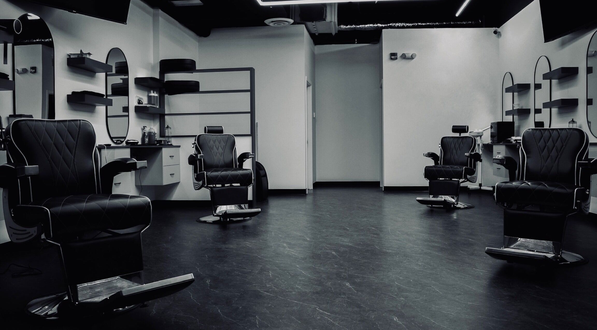 Modern interior of Platinum Barbershop in Edmonton, Alberta, CA, showcasing stylish black chairs and mirrors.