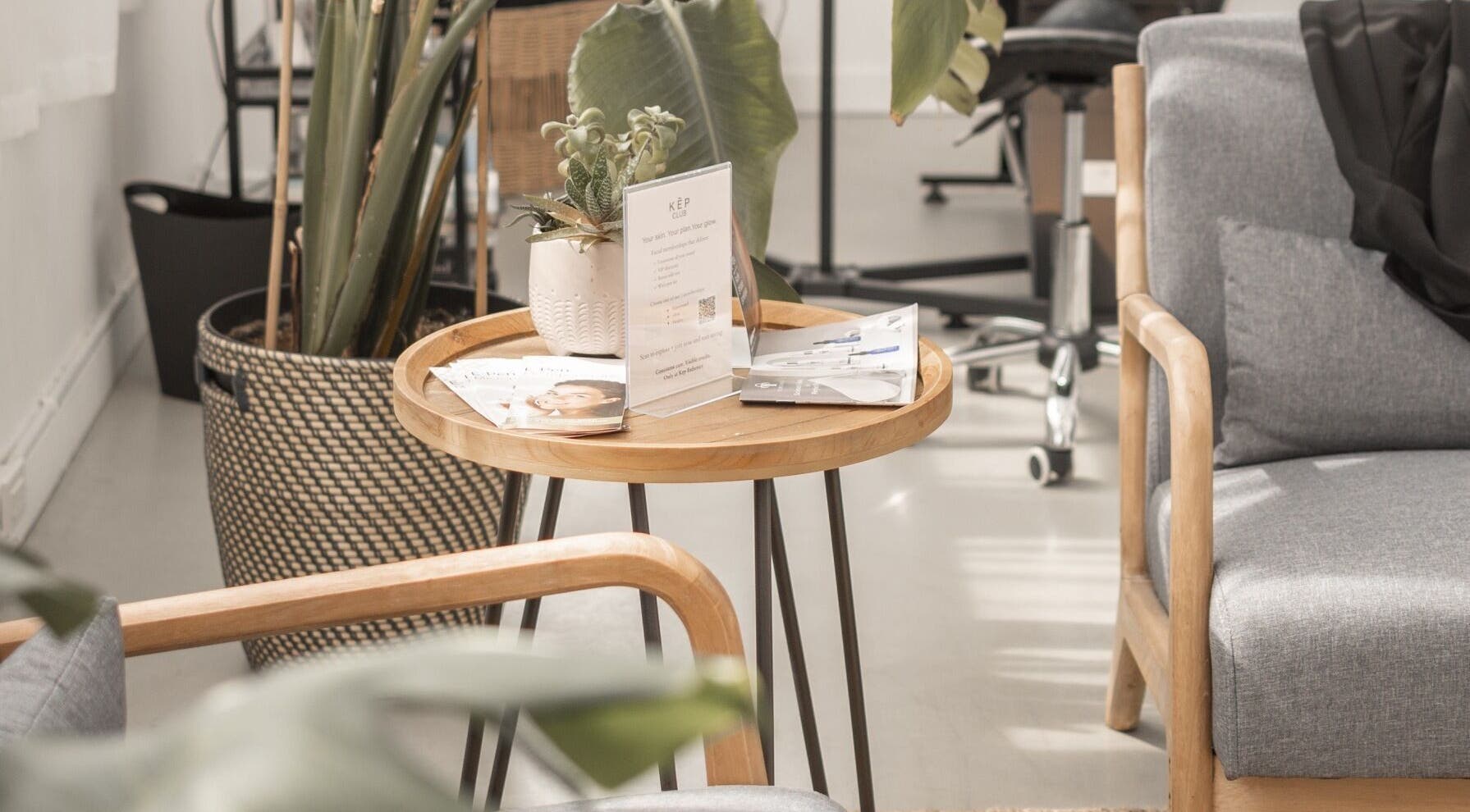 Cozy seating area at Kēp Esthetique, Montréal, Québec, CA with gray chairs and a wooden table with plant decor.