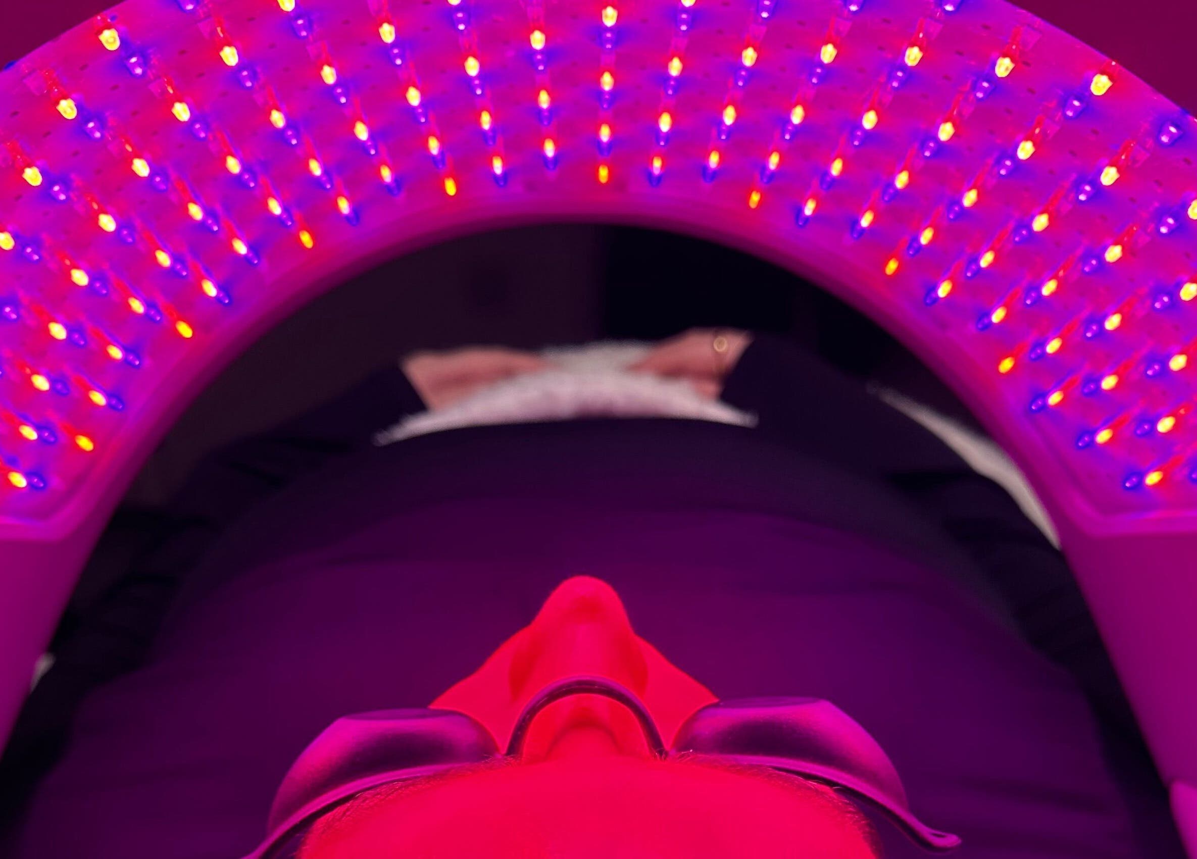A person receiving LED therapy at E.L Skin & Brows, Sheffield, England, GB, under vibrant red and blue lights.