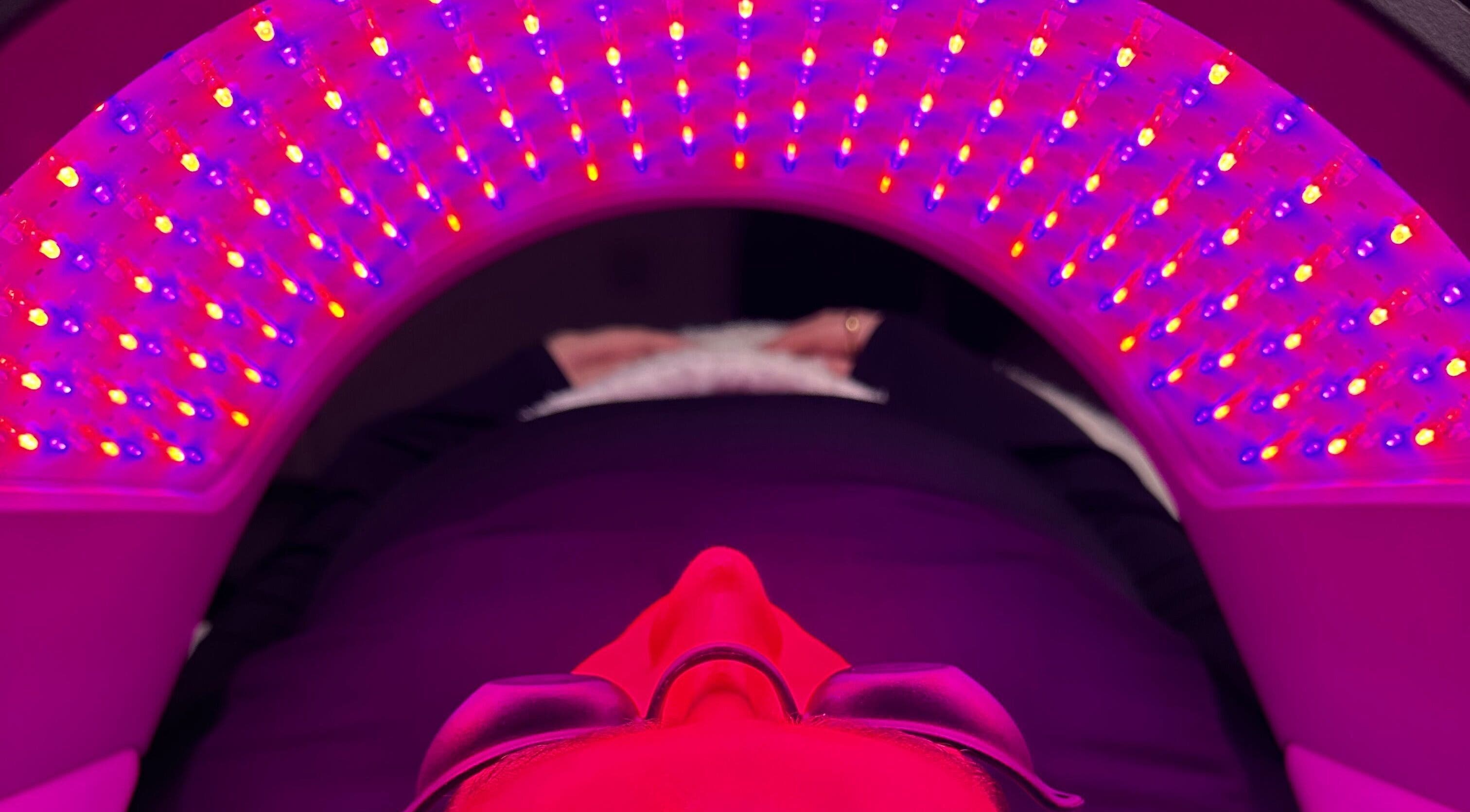 A person receiving LED therapy at E.L Skin & Brows, Sheffield, England, GB, under vibrant red and blue lights.