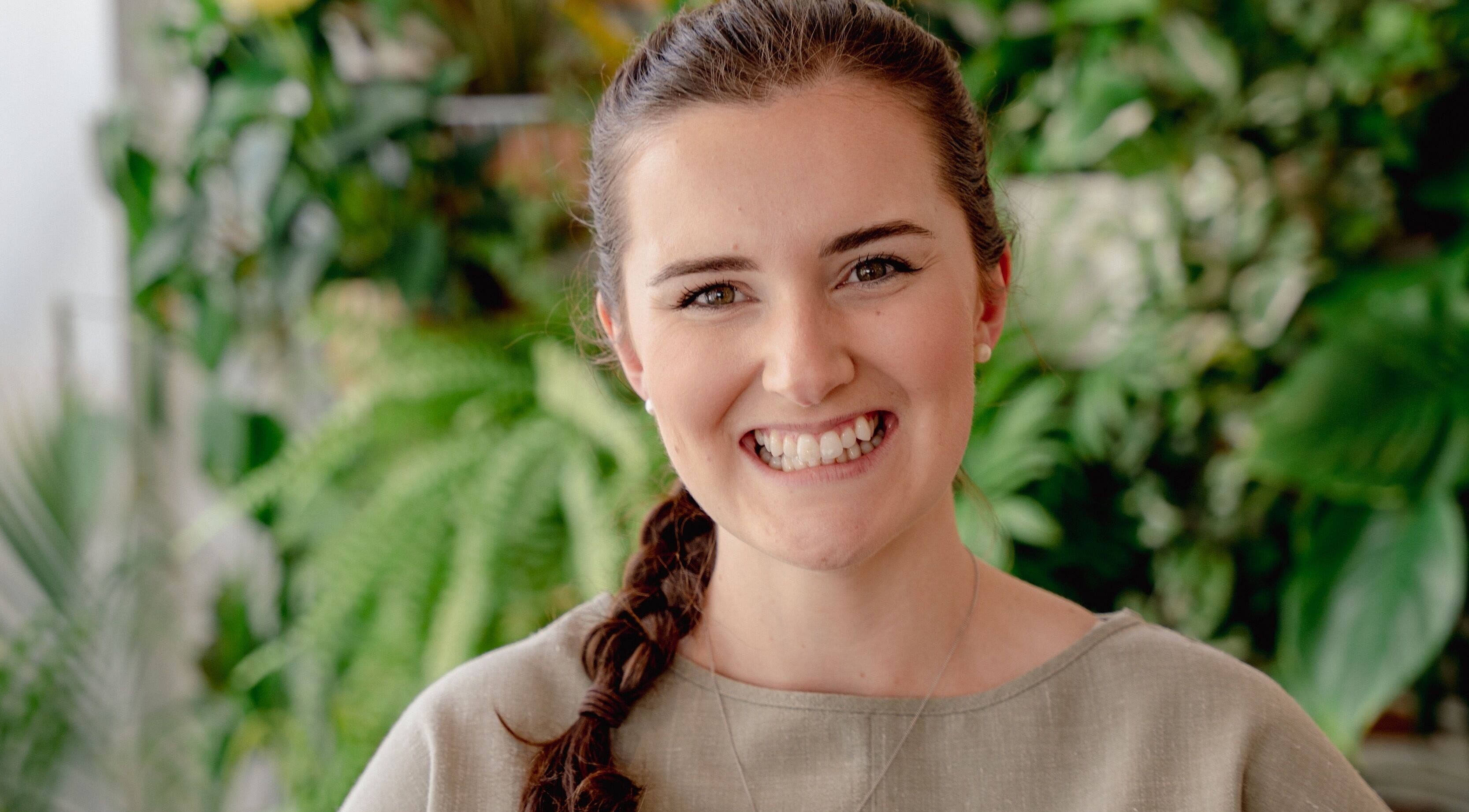 Smiling woman at Wellness with Hannah, Portsmouth, England, GB, surrounded by lush greenery.