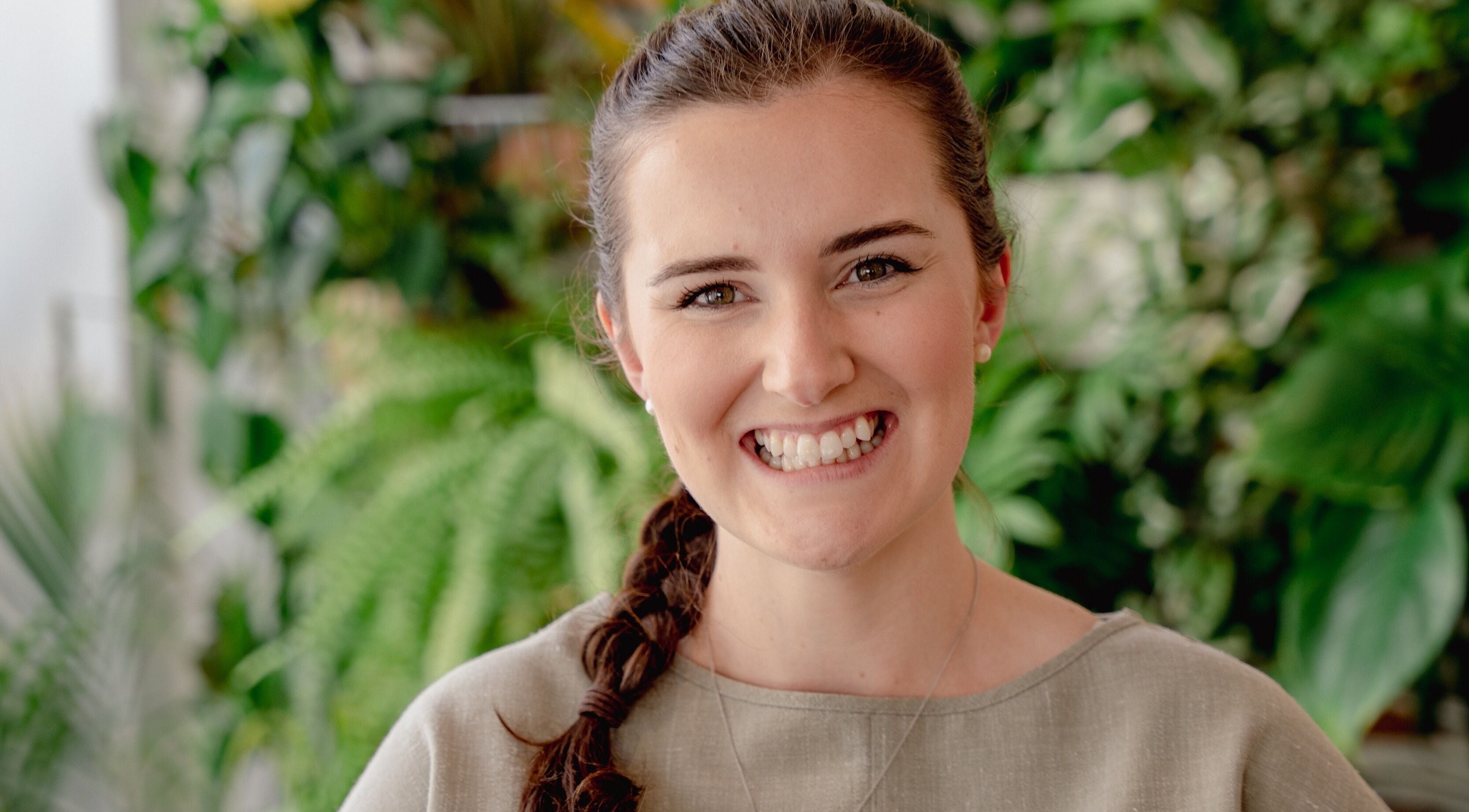 Smiling woman at Wellness with Hannah, Portsmouth, England, GB, surrounded by lush greenery.