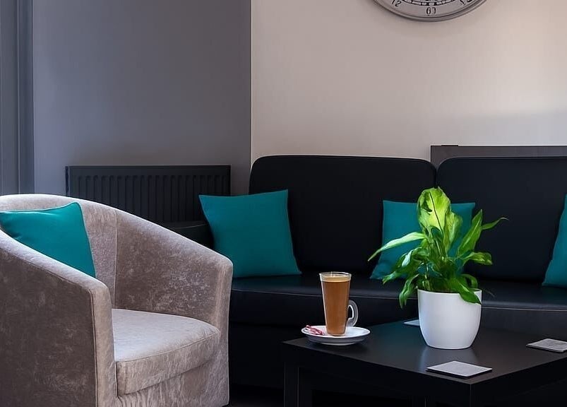 Inviting lounge area at Hideaway Hair Salon, Park Gate, England, GB with plush seating and a latte.
