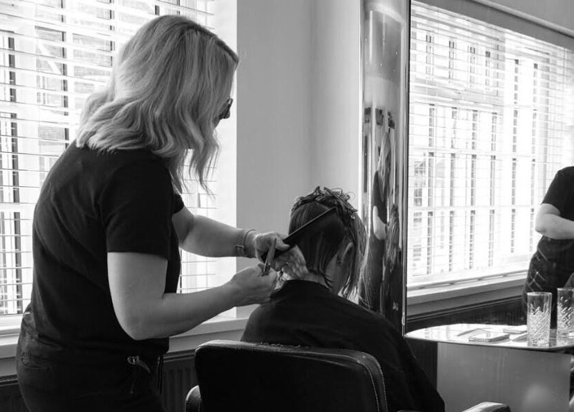 Stylist cutting hair at Hideaway Hair Salon, Park Gate, England, GB. Bright and welcoming interior.