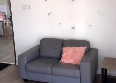 Comfortabele zithoek bij Finest Nails, Paramaribo, Paramaribo, SR met grijze bank en roze kussen.