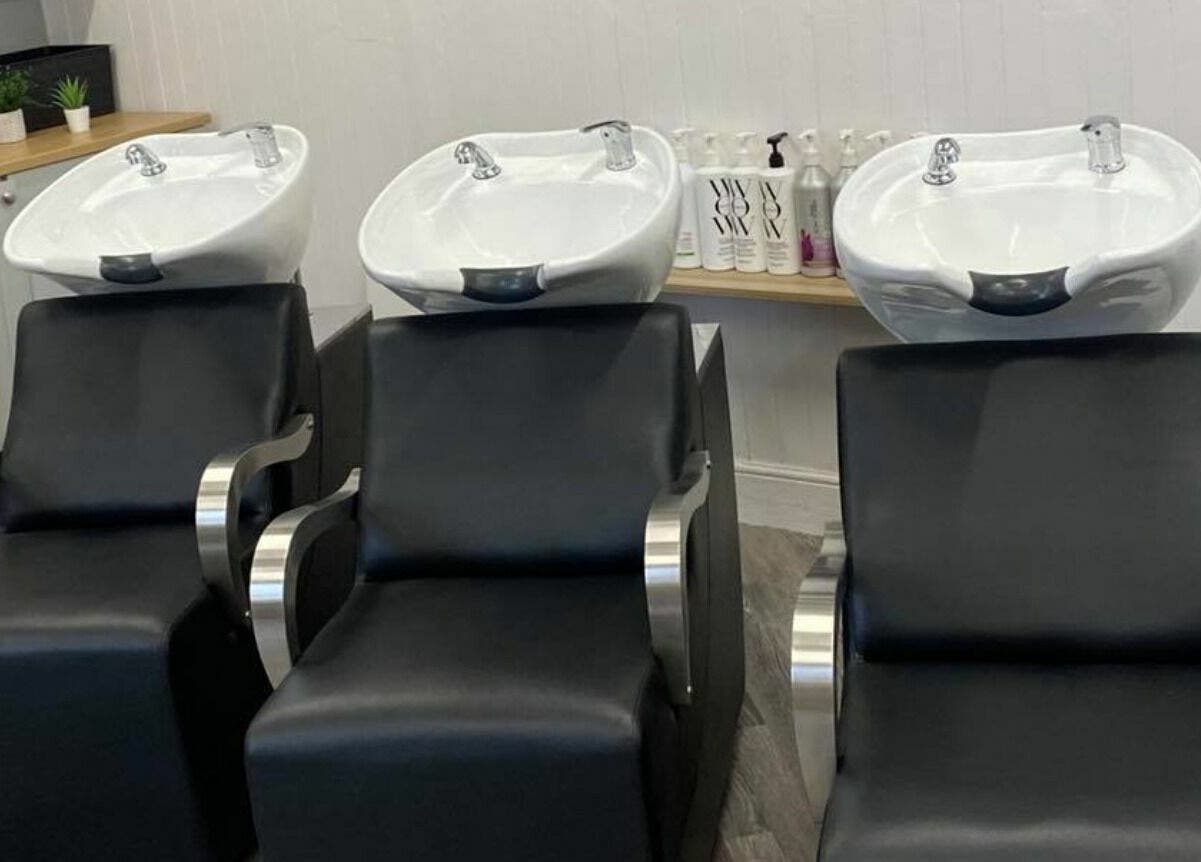 Modern wash stations at GH Hair Design, King's Lynn, England, GB, showcasing sleek black chairs in a stylish salon.