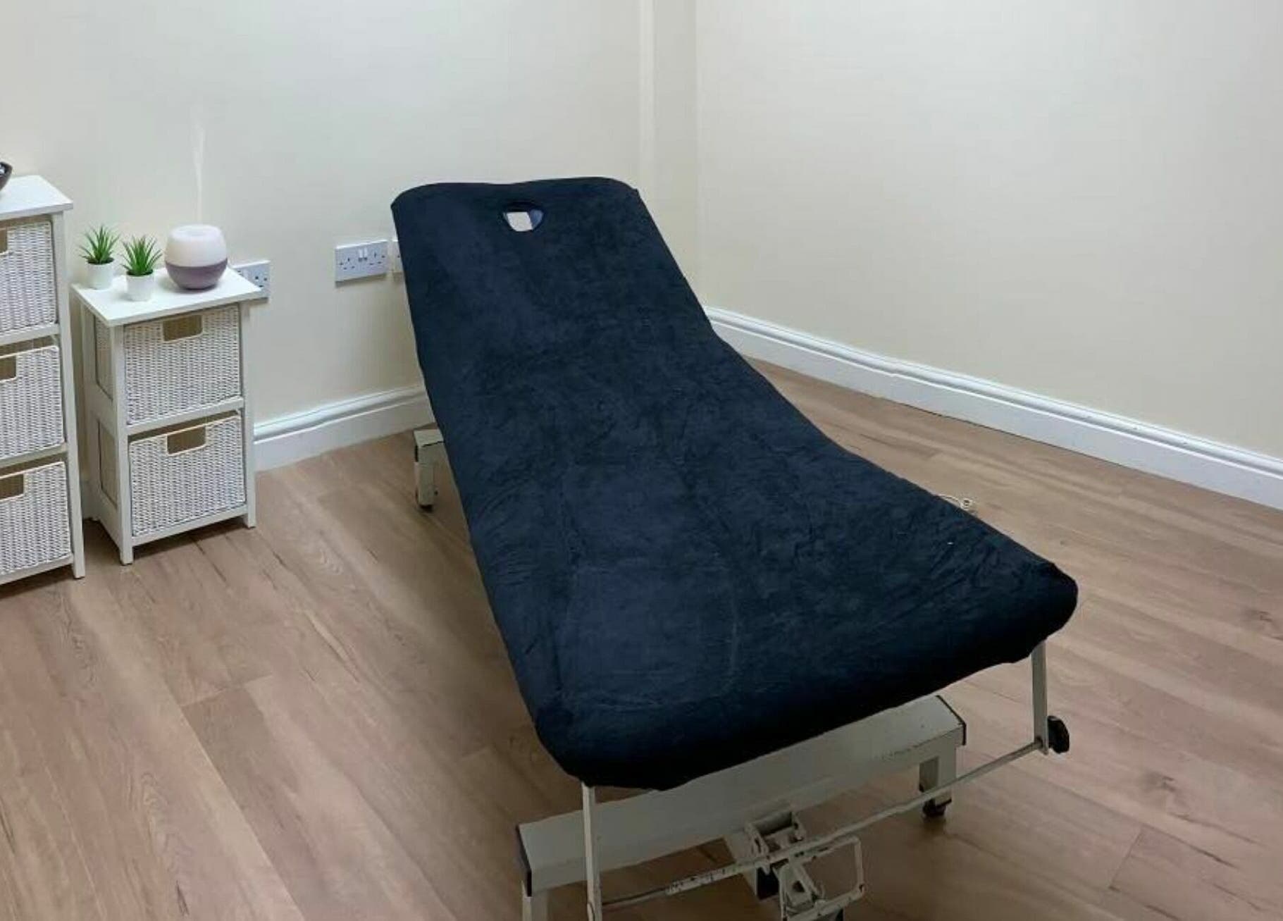 Relaxing treatment room at GH Hair Design, King's Lynn, England, GB features a cozy massage bed and chic storage.