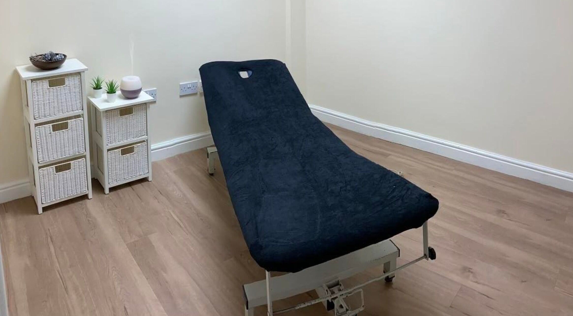 GH Hair Design spa room in King's Lynn, England, GB with cozy massage bed and white wicker drawers.