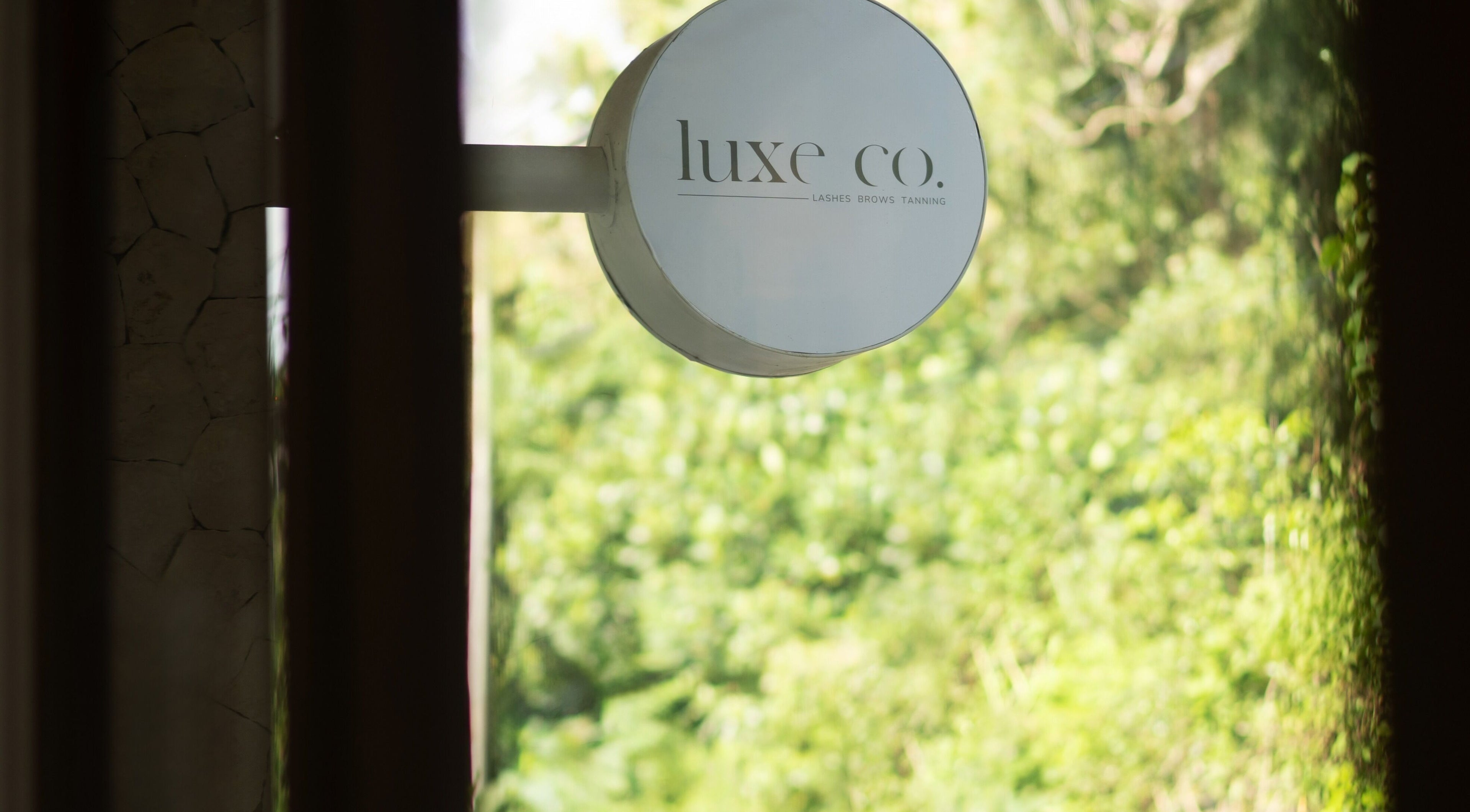 A stylish round sign of Luxe Co. Bali with lush greenery background, located in Bali, Bali, ID.