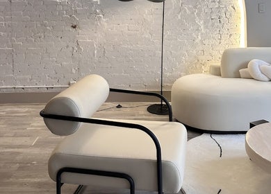 Modern lounge area at HELA Skincare- Midtown, New York, New York, US with sleek furnishings and exposed brick wall.