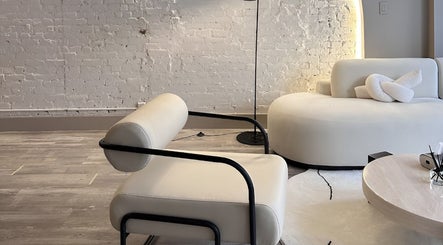 Modern lounge area at HELA Skincare- Midtown, New York, New York, US with sleek furnishings and exposed brick wall.