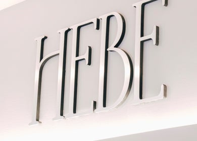 Elegant signage of HELA Skincare- SoHo, New York, New York, US, showcasing sleek metallic letters.
