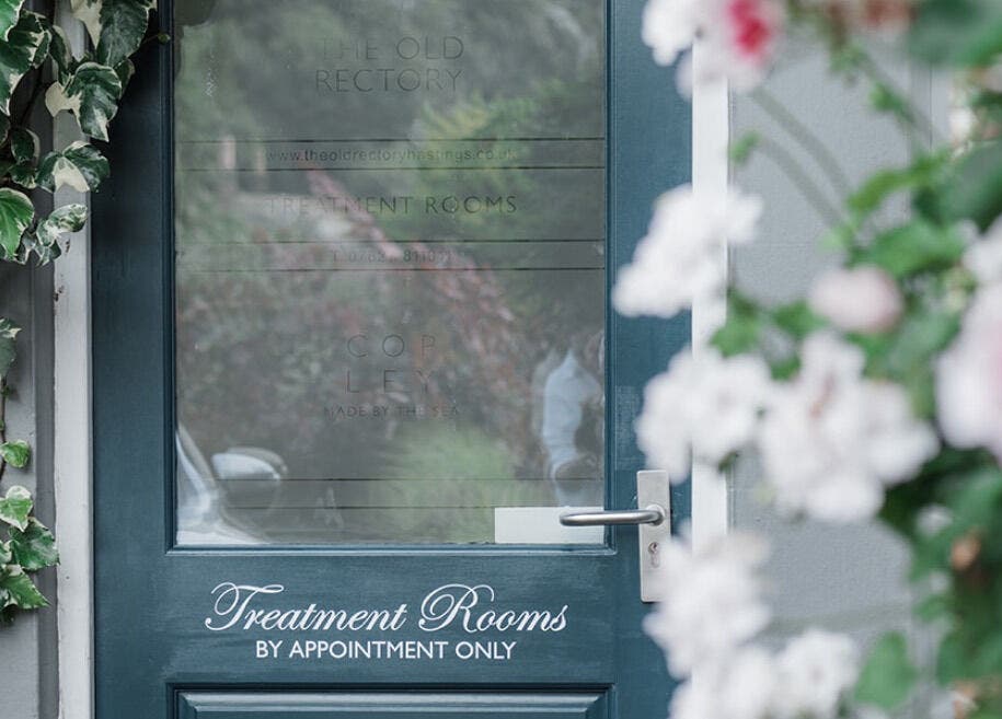 Front door of Treatment Rooms in Hastings, England, GB, surrounded by lush ivy and blooms.