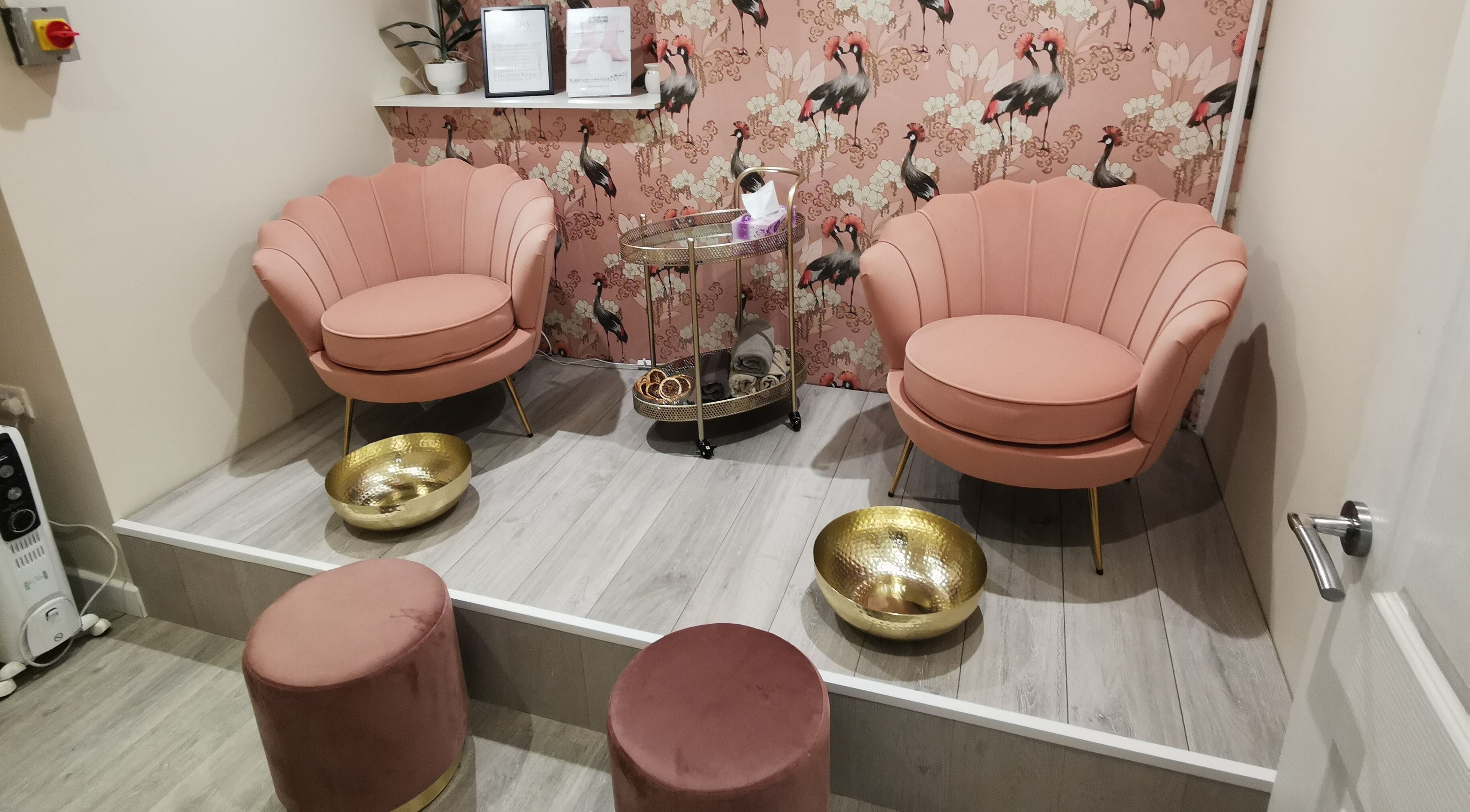 Elegant pedicure chairs with gold bowls at Vanity, Leicester, England, GB, featuring bird-themed wallpaper.