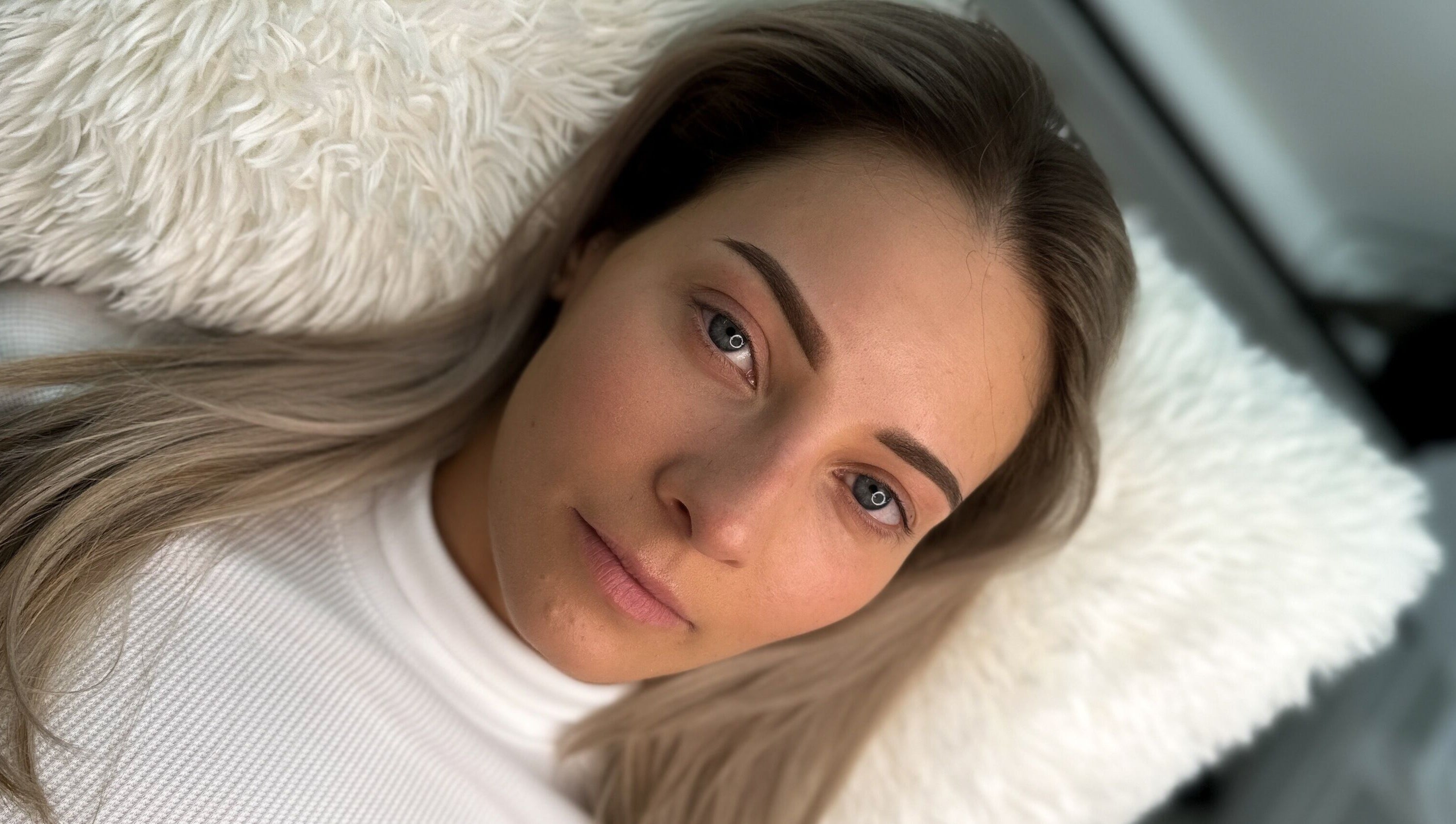 Client with beautifully shaped eyebrows, styled at The Brow Mami in Hamilton, Ontario, CA, relaxing on a plush pillow.