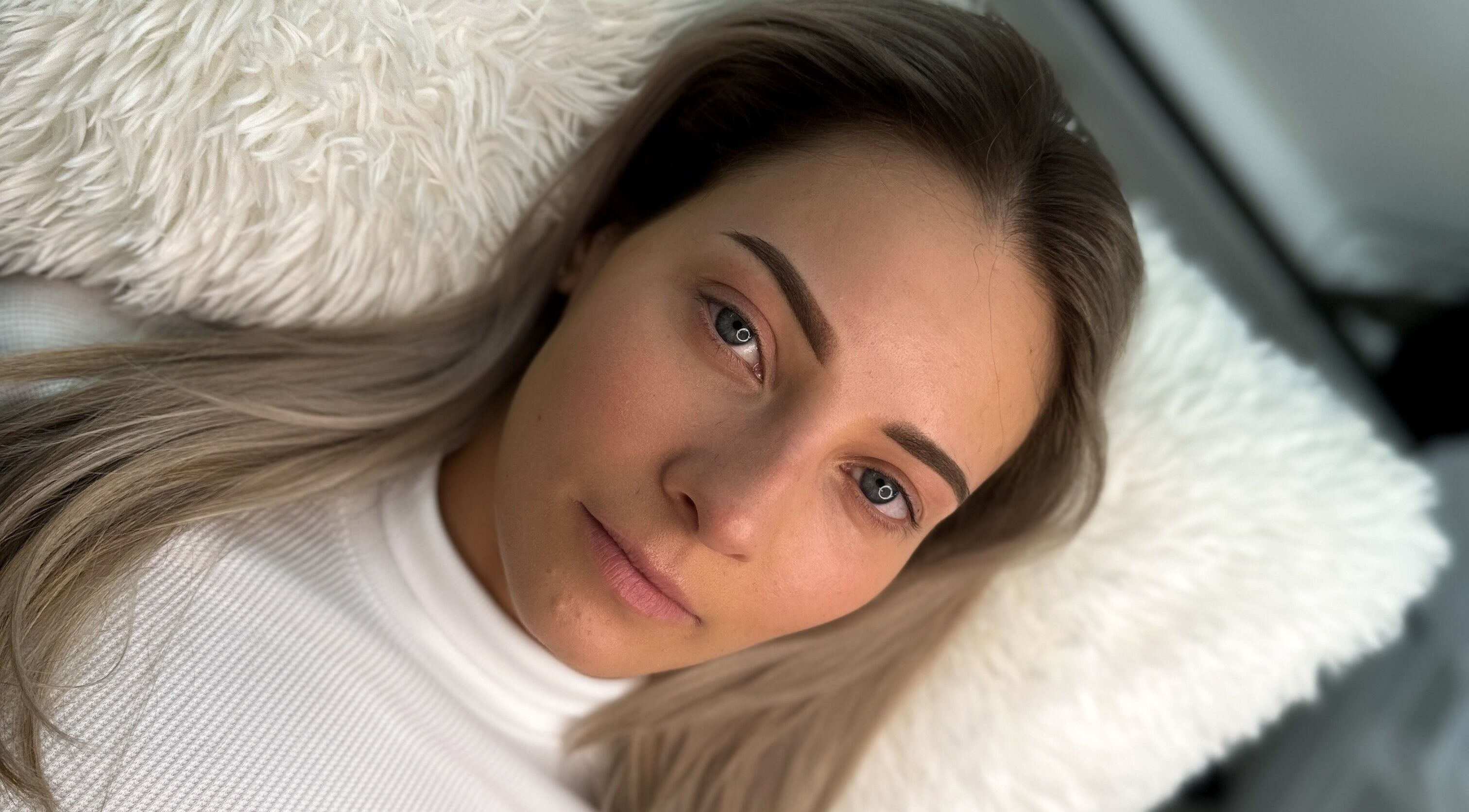 Client with beautifully shaped eyebrows, styled at The Brow Mami in Hamilton, Ontario, CA, relaxing on a plush pillow.