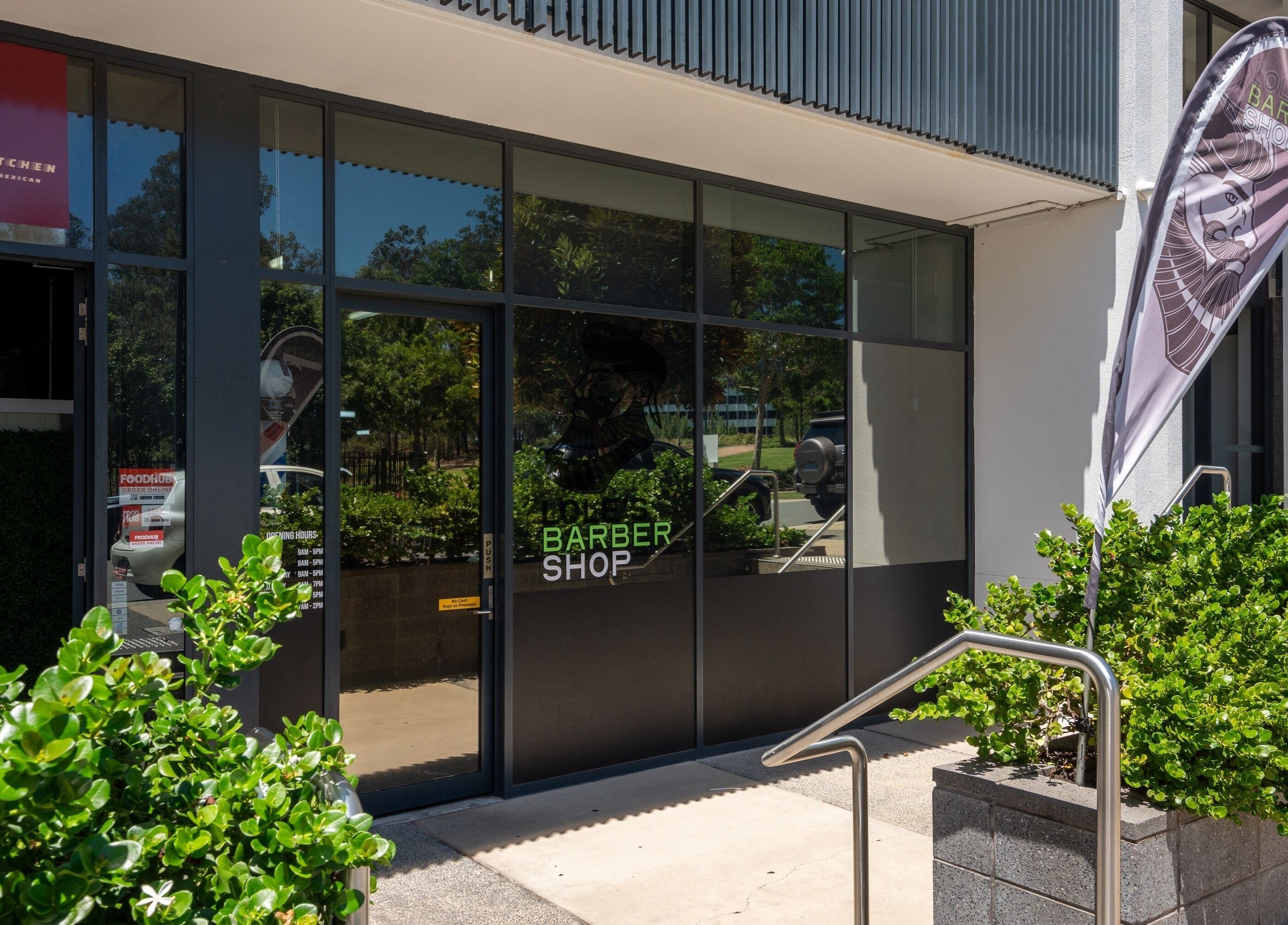 Entrance of Lole's Barber Shop - Ian Keilar Drive, Springfield Central, QLD, AU with vibrant greenery.