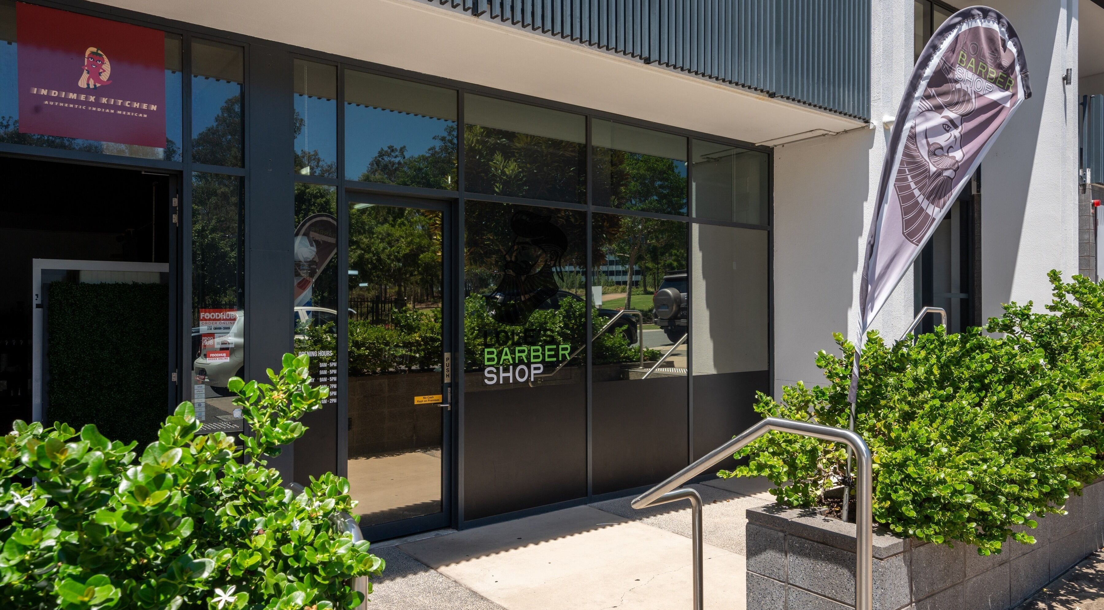 Entrance of Lole's Barber Shop - Ian Keilar Drive, Springfield Central, QLD, AU with vibrant greenery.