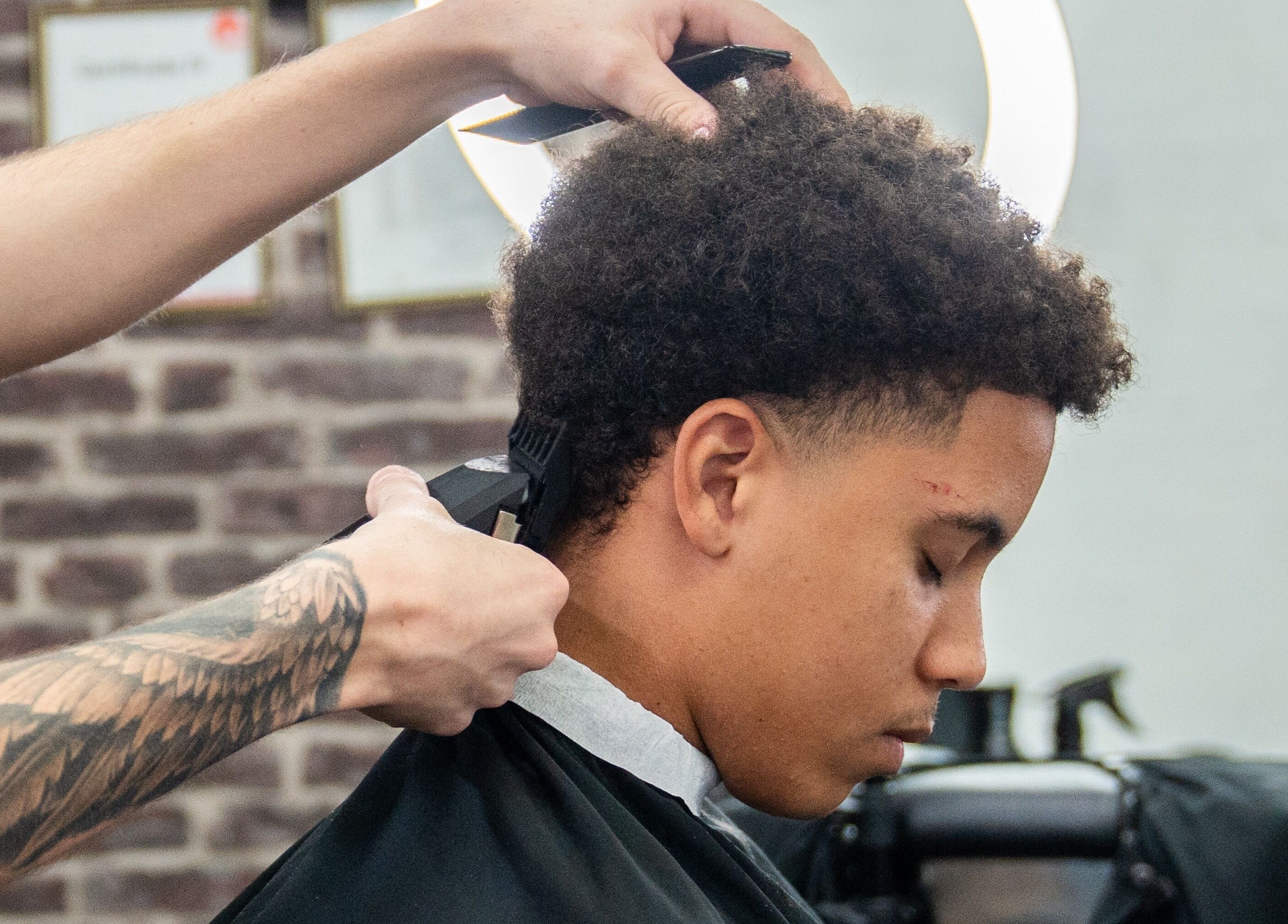 A stylist trims a customer's hair at Lole's Barber Shop - Ian Keilar Drive, Springfield Central, QLD, AU.