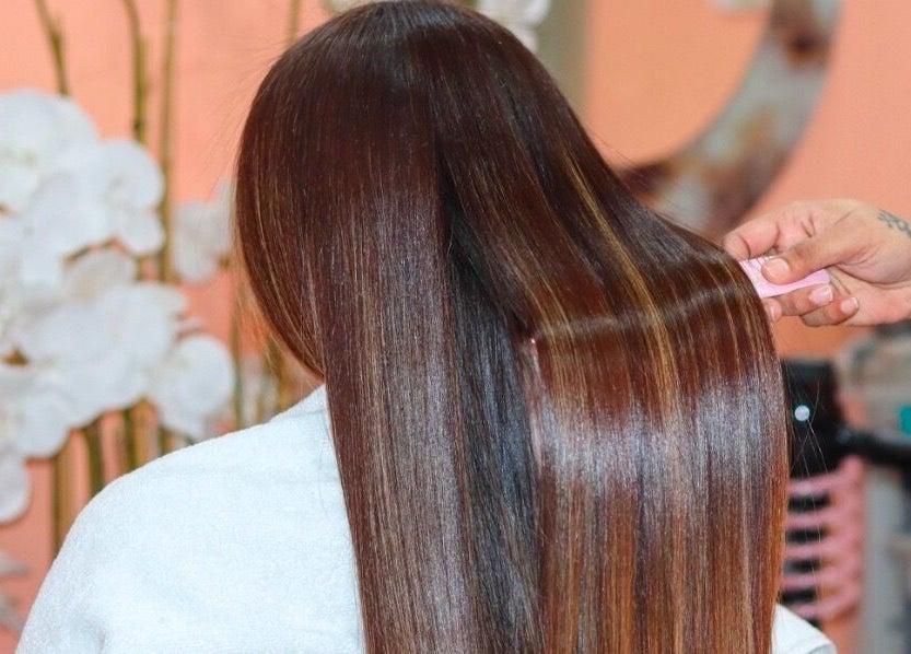 Am Grace & Glam Beauty Center Arjan Dubai stylist smoothing long shiny hair, Dubai, AE.