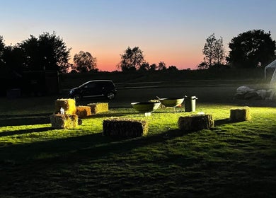 Hay bales and tables under a sunset at Kamala Fest in Winnersh, England, GB.