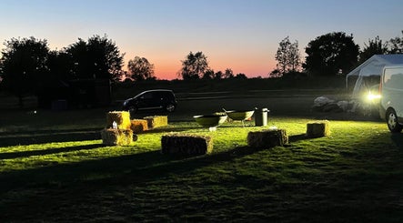 Hay bales and tables under a sunset at Kamala Fest in Winnersh, England, GB.