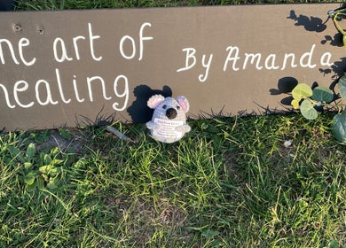 Art of healing sign with koala at Kamala Fest, Winnersh, England, GB, surrounded by greenery.