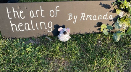 Art of healing sign with koala at Kamala Fest, Winnersh, England, GB, surrounded by greenery.
