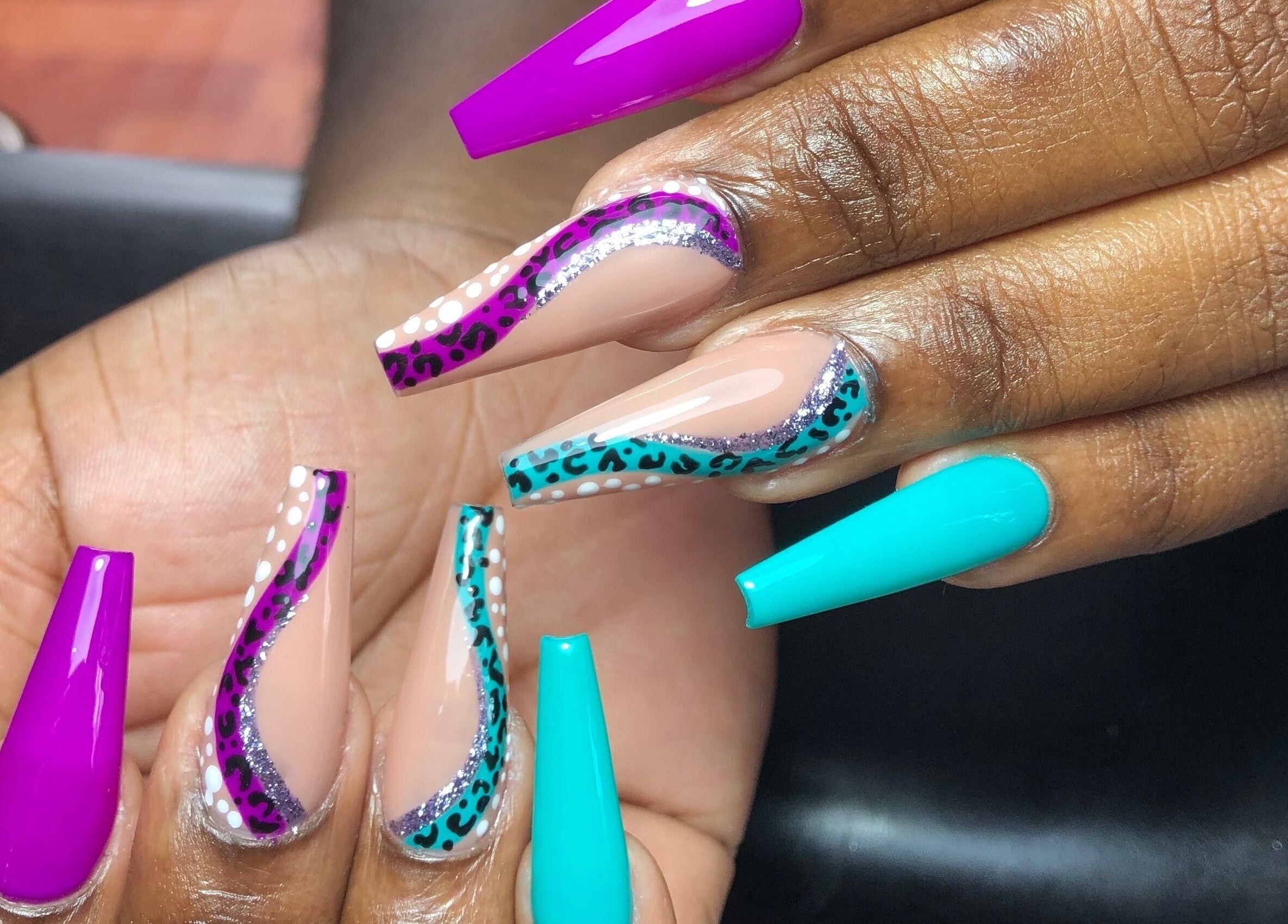 Stylish vibrant nail art at The Butterfly Nail Lounge, Bridgetown, Saint Peter, BB showcasing purple and teal designs.