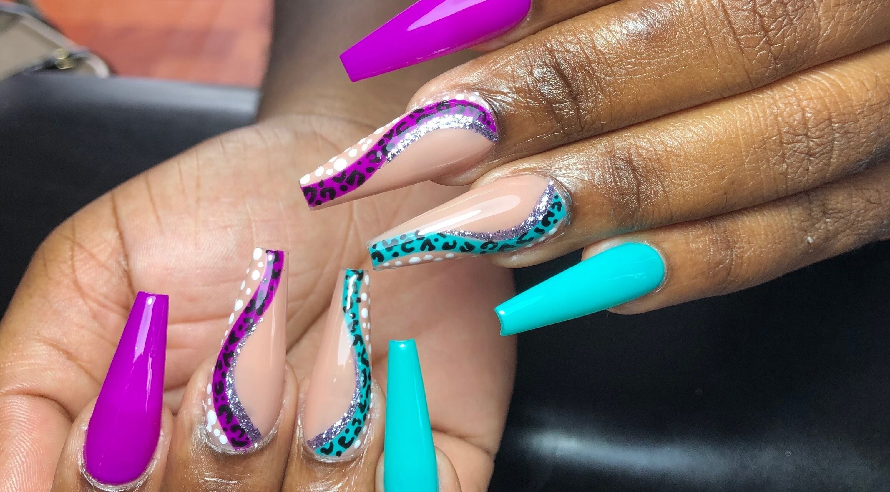 Stylish vibrant nail art at The Butterfly Nail Lounge, Bridgetown, Saint Peter, BB showcasing purple and teal designs.