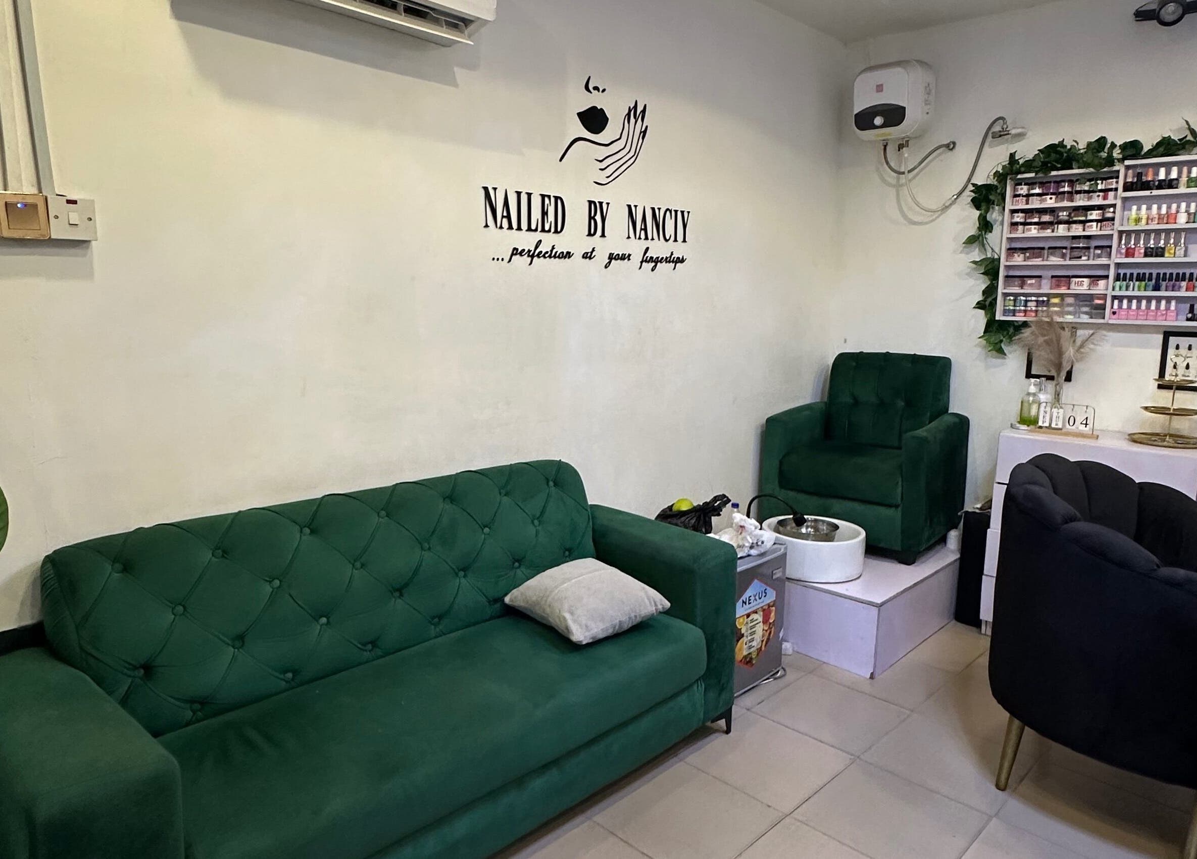 Nailed by Nanciy's elegant nail salon in Port Harcourt, Rivers, NG with stylish green sofas and polish display.