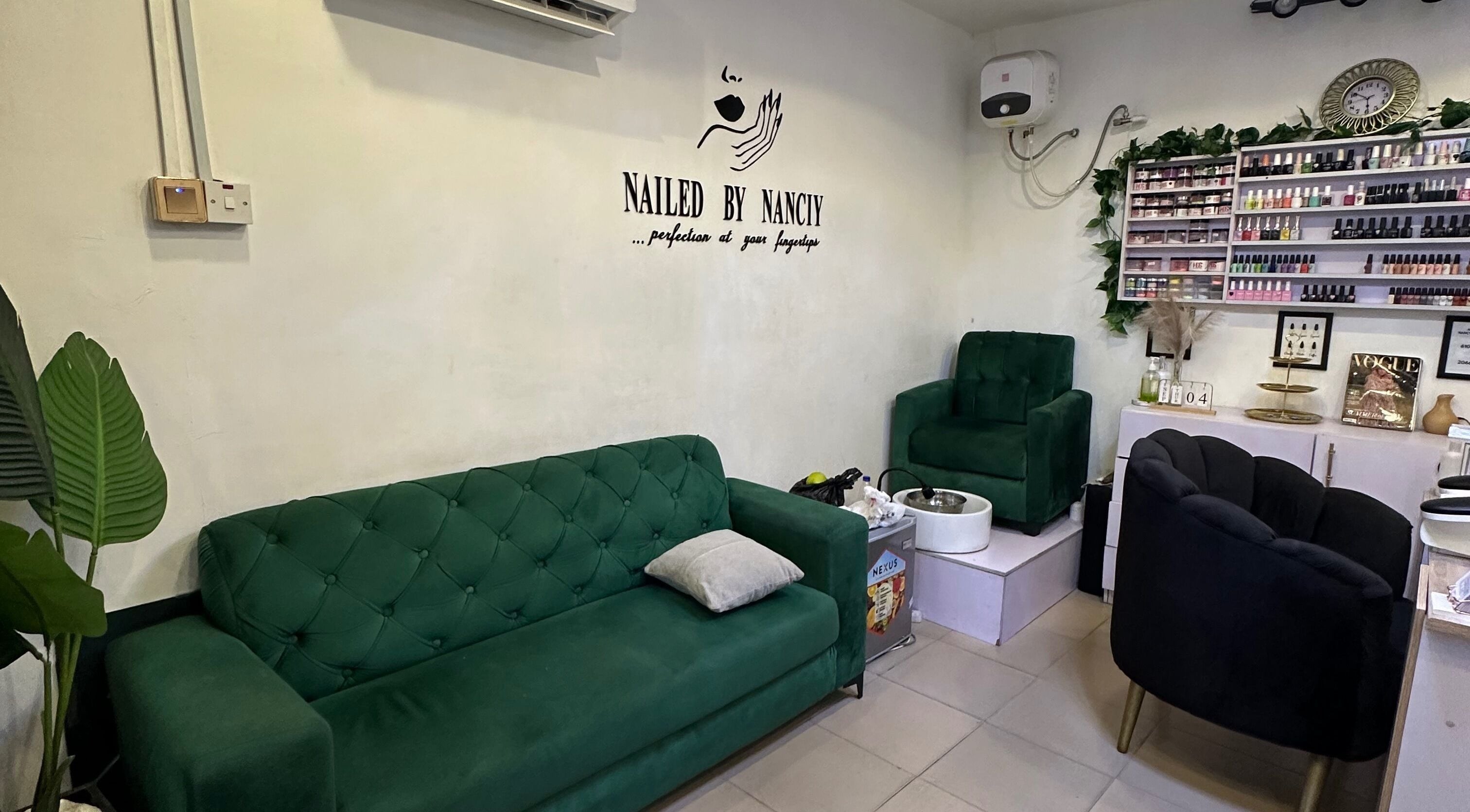 Nailed by Nanciy's elegant nail salon in Port Harcourt, Rivers, NG with stylish green sofas and polish display.