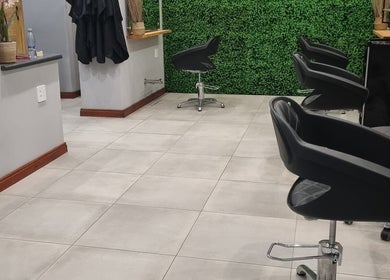 Stylish salon seating at Hair Aroma, Pretoria, Gauteng, ZA, featuring sleek black chairs and greenery wall.