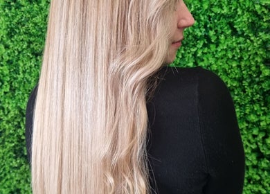 Blonde hair styled sleekly at Hair Aroma in Pretoria, Gauteng, ZA against a lush green backdrop.
