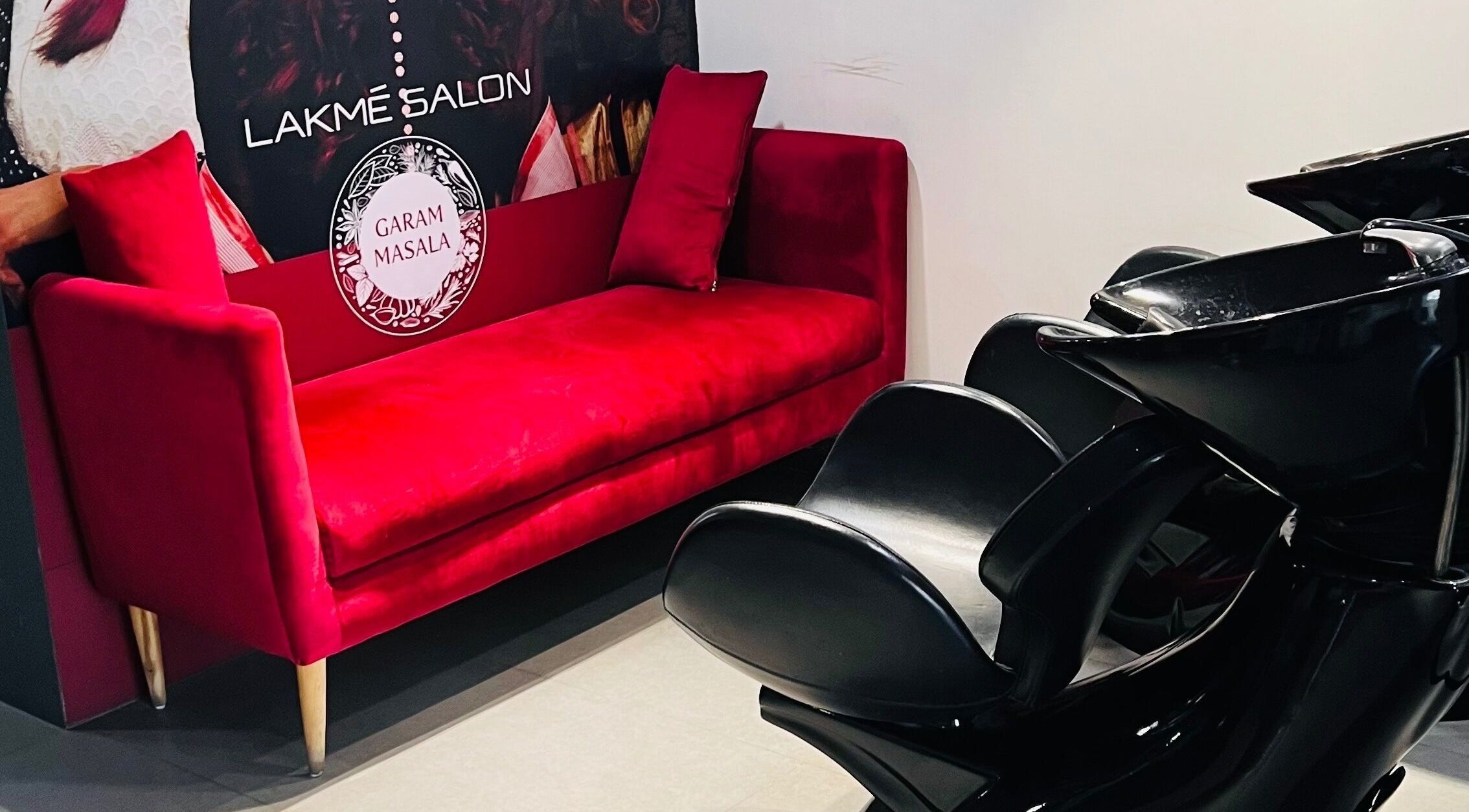 Red couch and black chairs at Lakme Salon Kompally, Hyderabad, Telangana, IN showcase elegant salon setting.