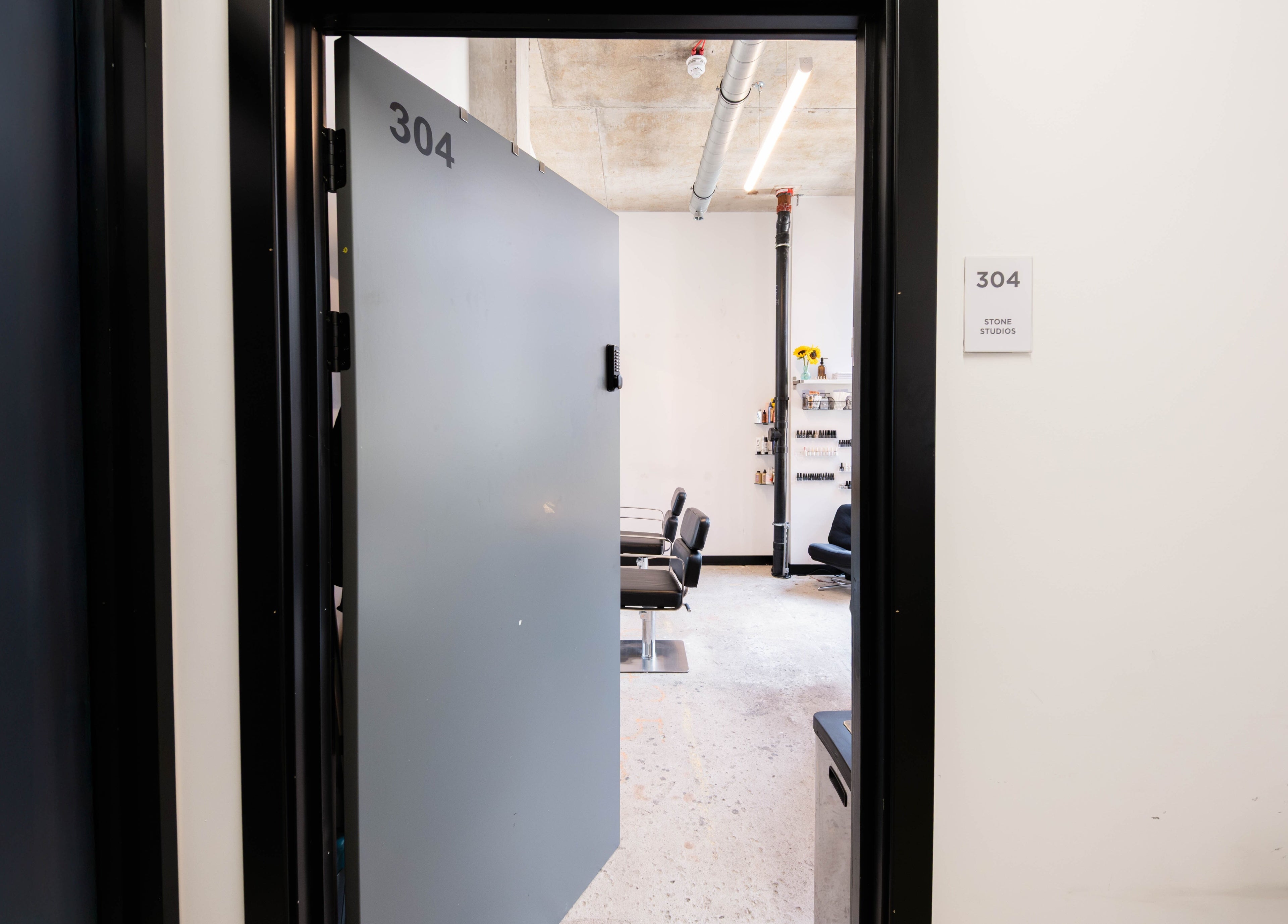 Open door leads to stylish salon space at SPACE5 in London, GB featuring modern decor and sleek chairs.