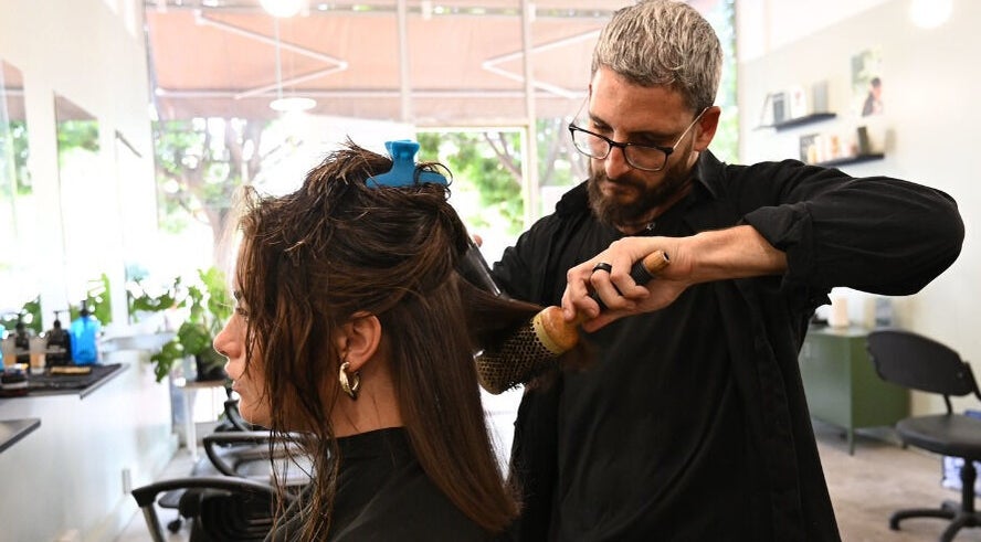 Expert stylist at Birdhaven Studio in Johannesburg, Gauteng, ZA, blow-drying a client's hair with precision.