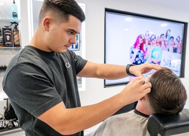 Barber expertly styling a client's hair at Grays Grooming For Men in Ewell, England, GB.