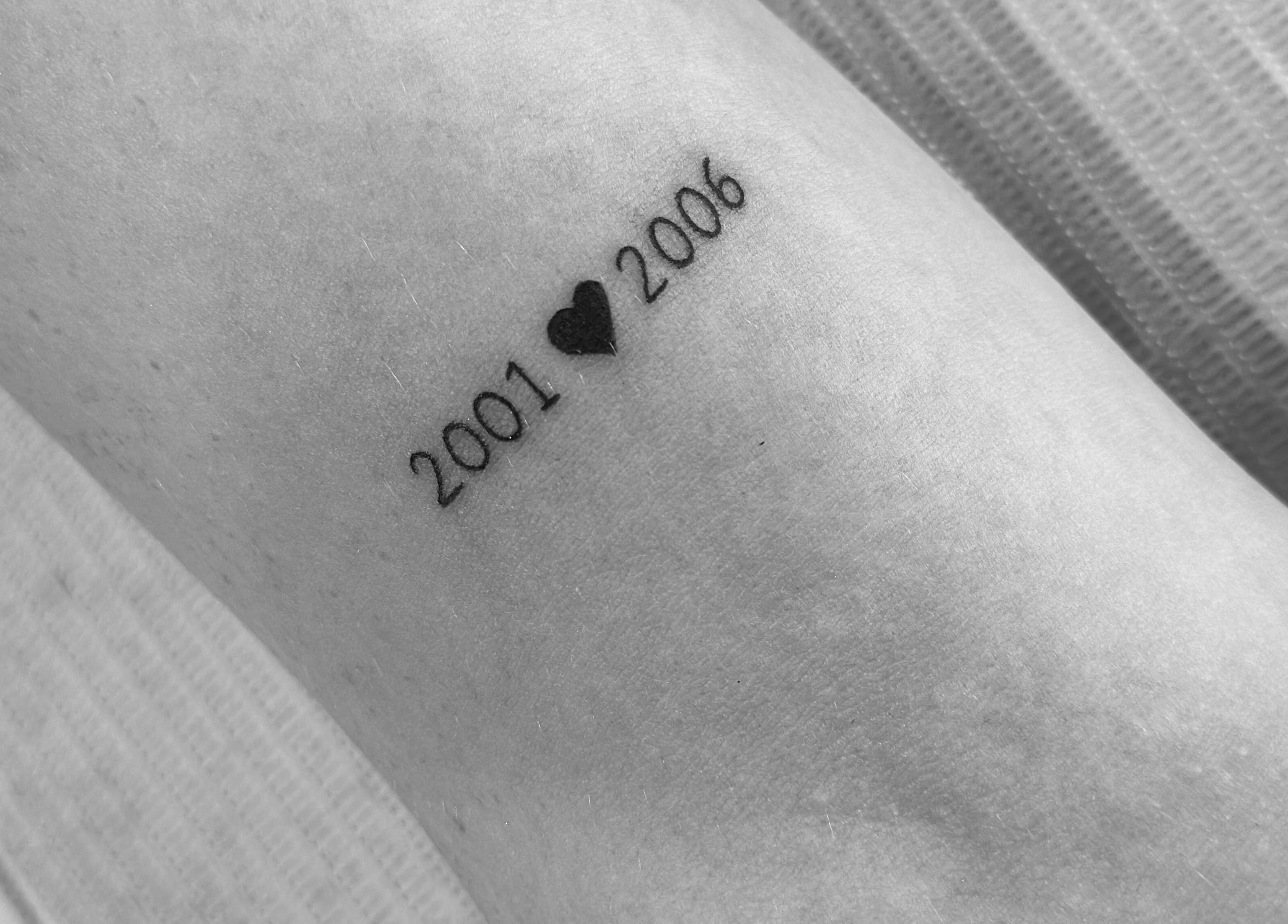 Minimalist tattoo of dates with heart at Nataly at Meadow & Charm - Council Bluffs, Iowa, US.