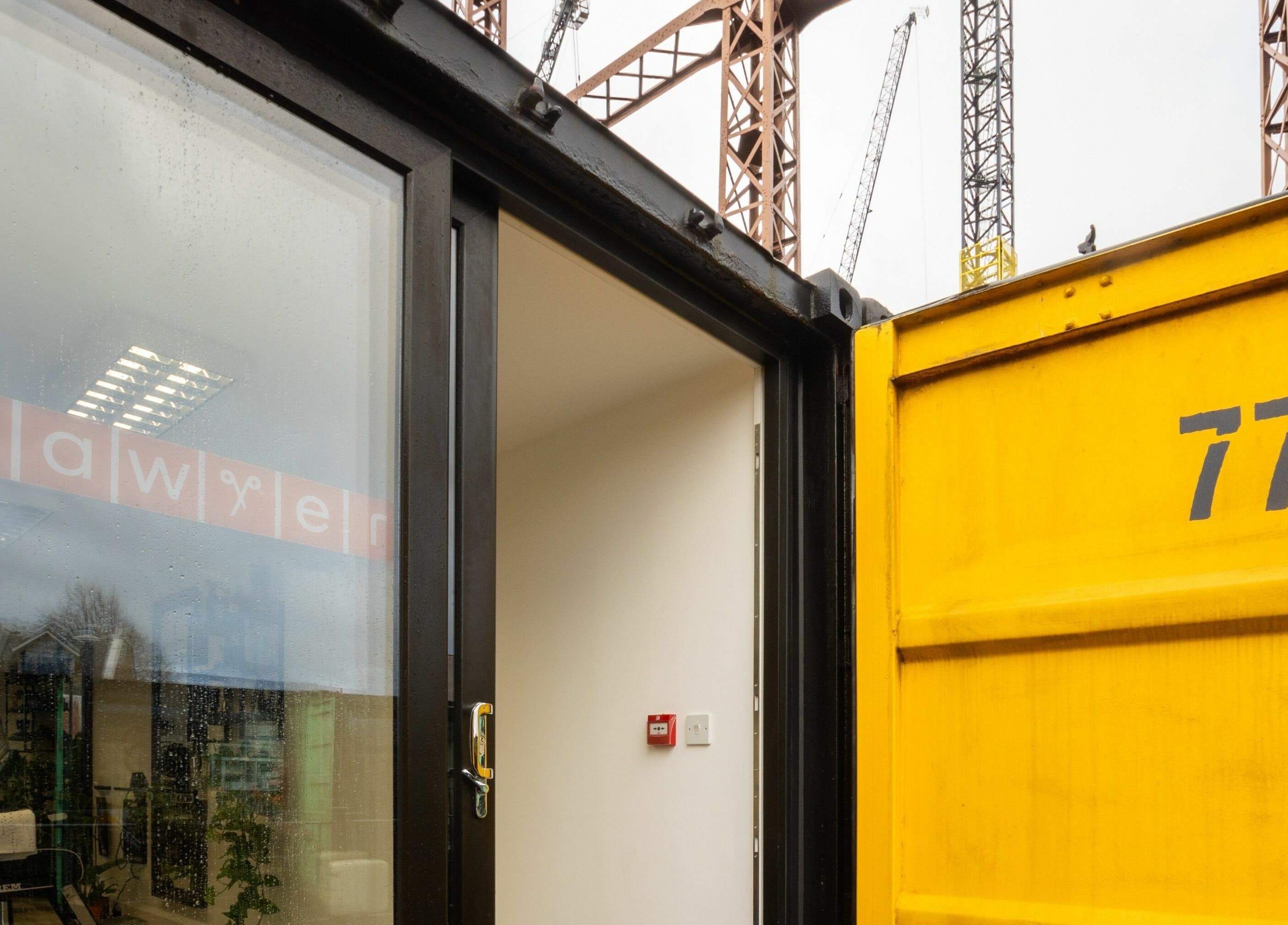 Entrance to Sawyer salon in a bright container unit at London, England, GB with visible yellow door.