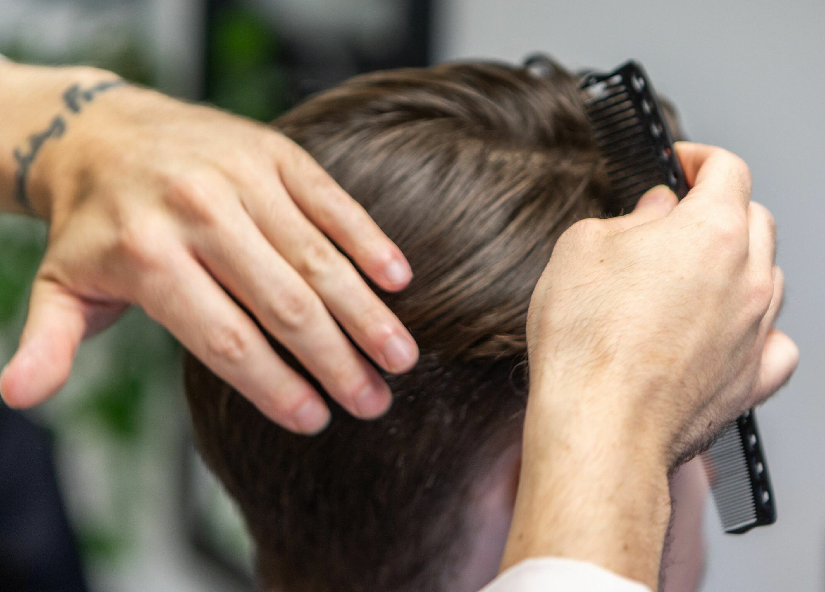 Hair stylist combing client's hair at Sawyer, London, England, GB.