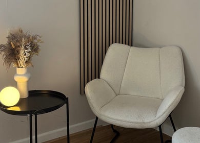 Elegant seating area with modern decor at Enhance Studios in Christchurch, GB, featuring a plush chair and vase.