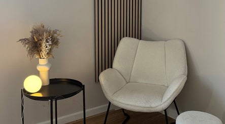 Elegant seating area with modern decor at Enhance Studios in Christchurch, GB, featuring a plush chair and vase.