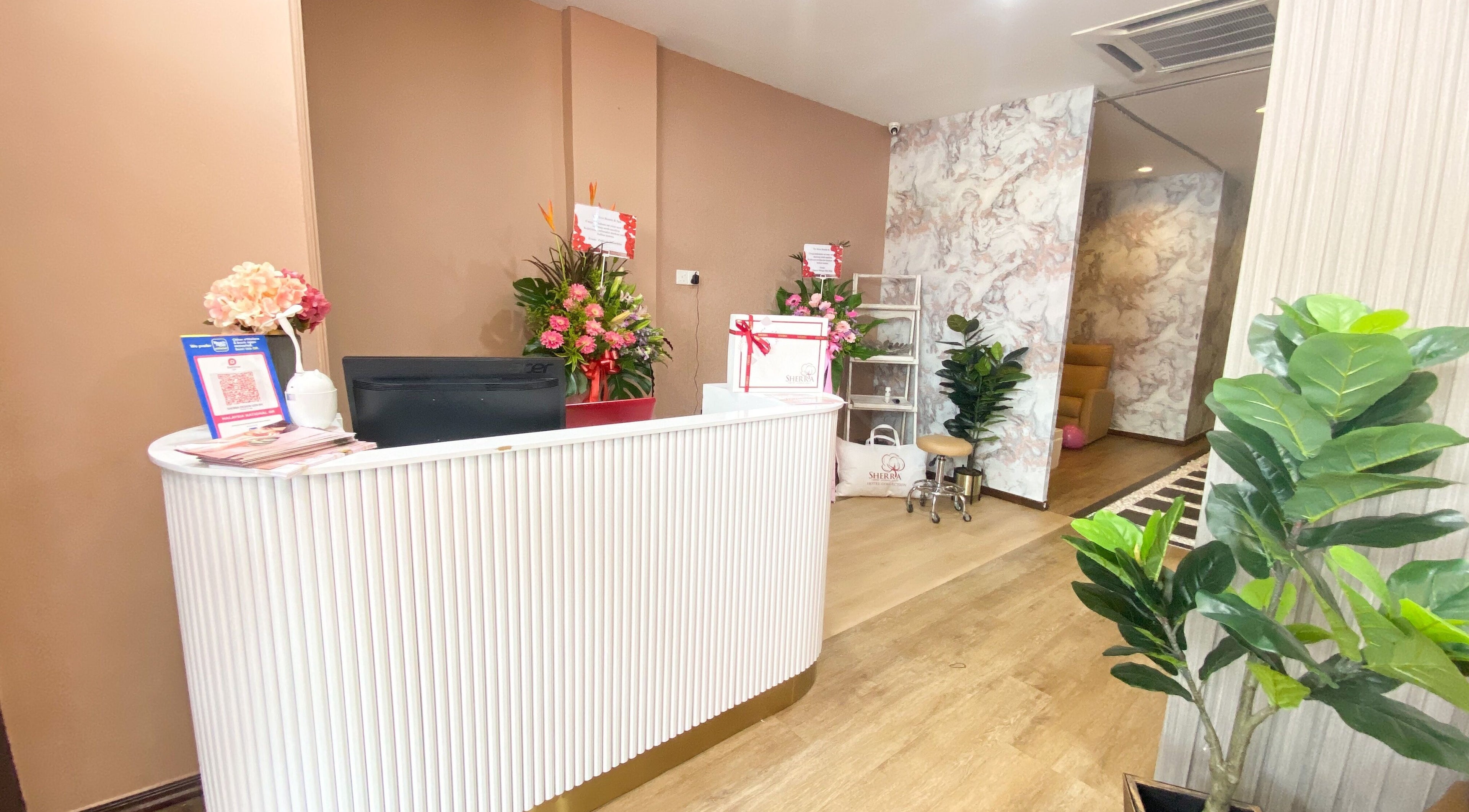 Reception area of Hera Beaute Spa in Nilai, Negeri Sembilan, MY, featuring a stylish white desk and vibrant flowers.