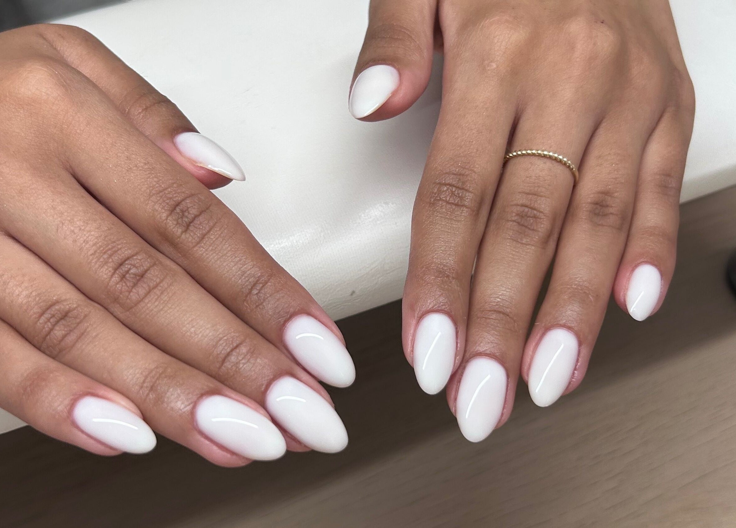 Close-up of manicured hands with white nails at MANI Studio, Victoria, Victoria, AU.
