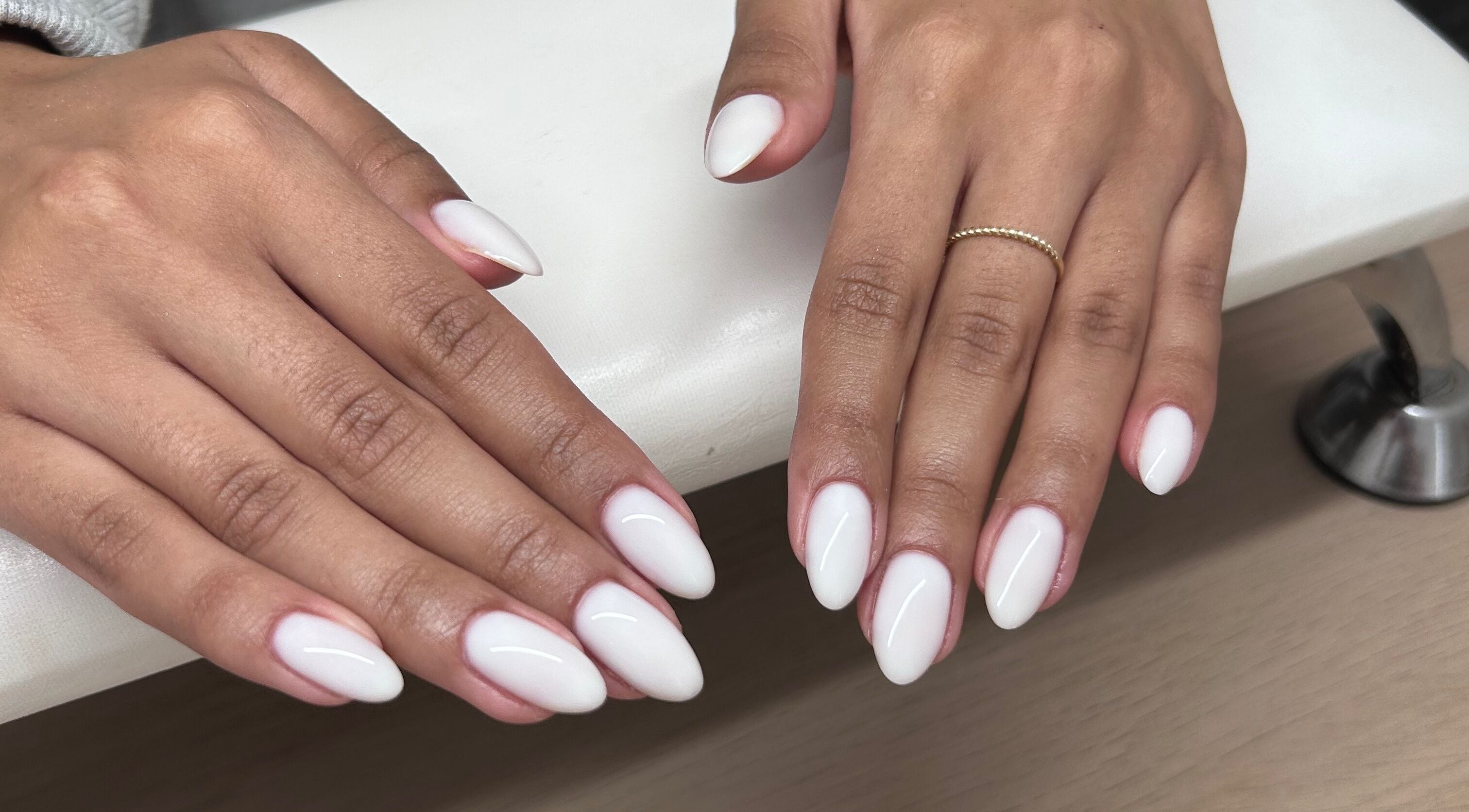 Close-up of manicured hands with white nails at MANI Studio, Victoria, Victoria, AU.