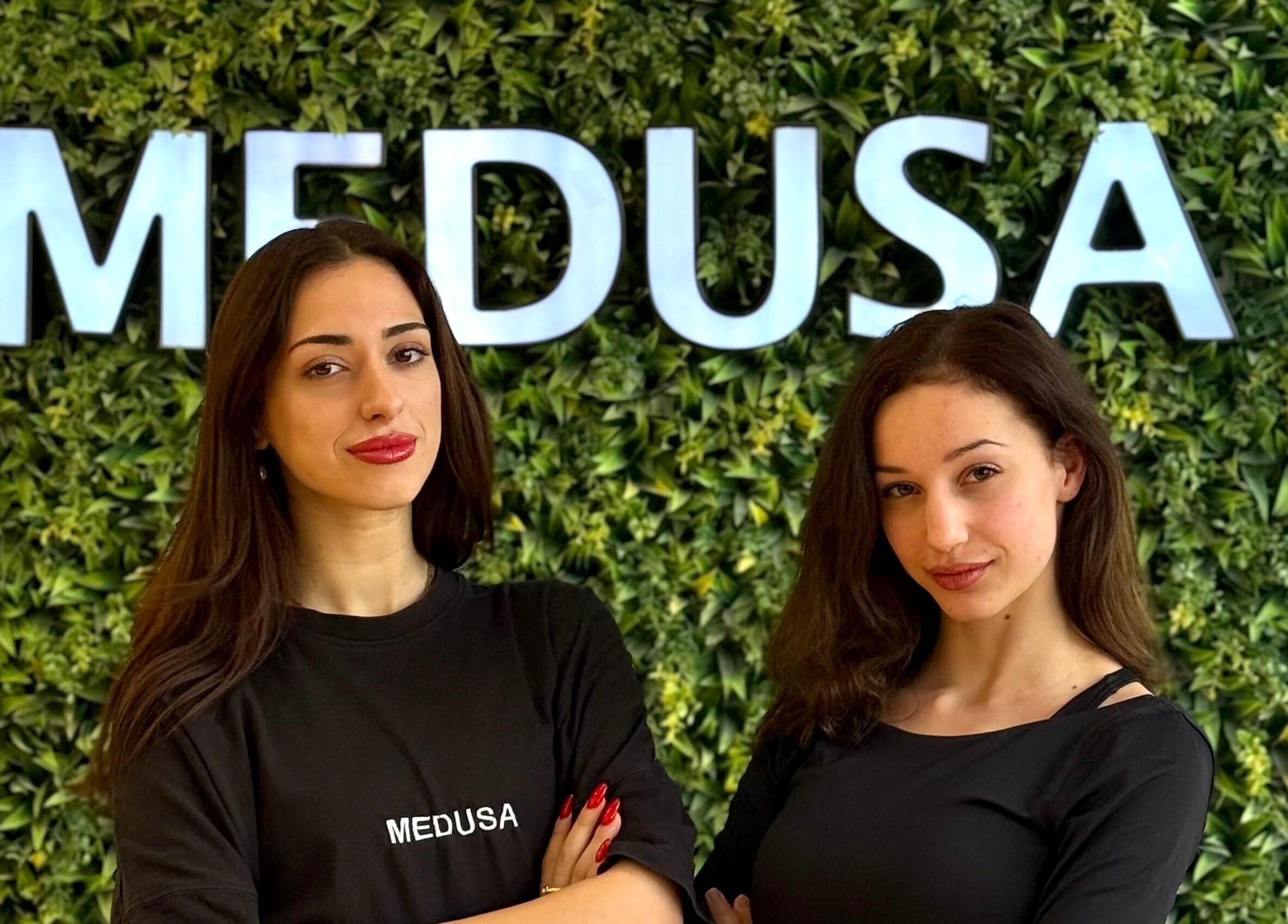 Δύο υπάλληλοι στο Medusa Barber Delfon στη Θεσσαλονίκη, GR, με φόντο πράσινο τοίχο.