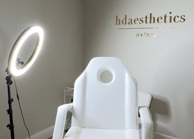 A modern treatment room at HD Aesthetics Oxford in Kidlington, England, GB with a sleek white chair and ring light.